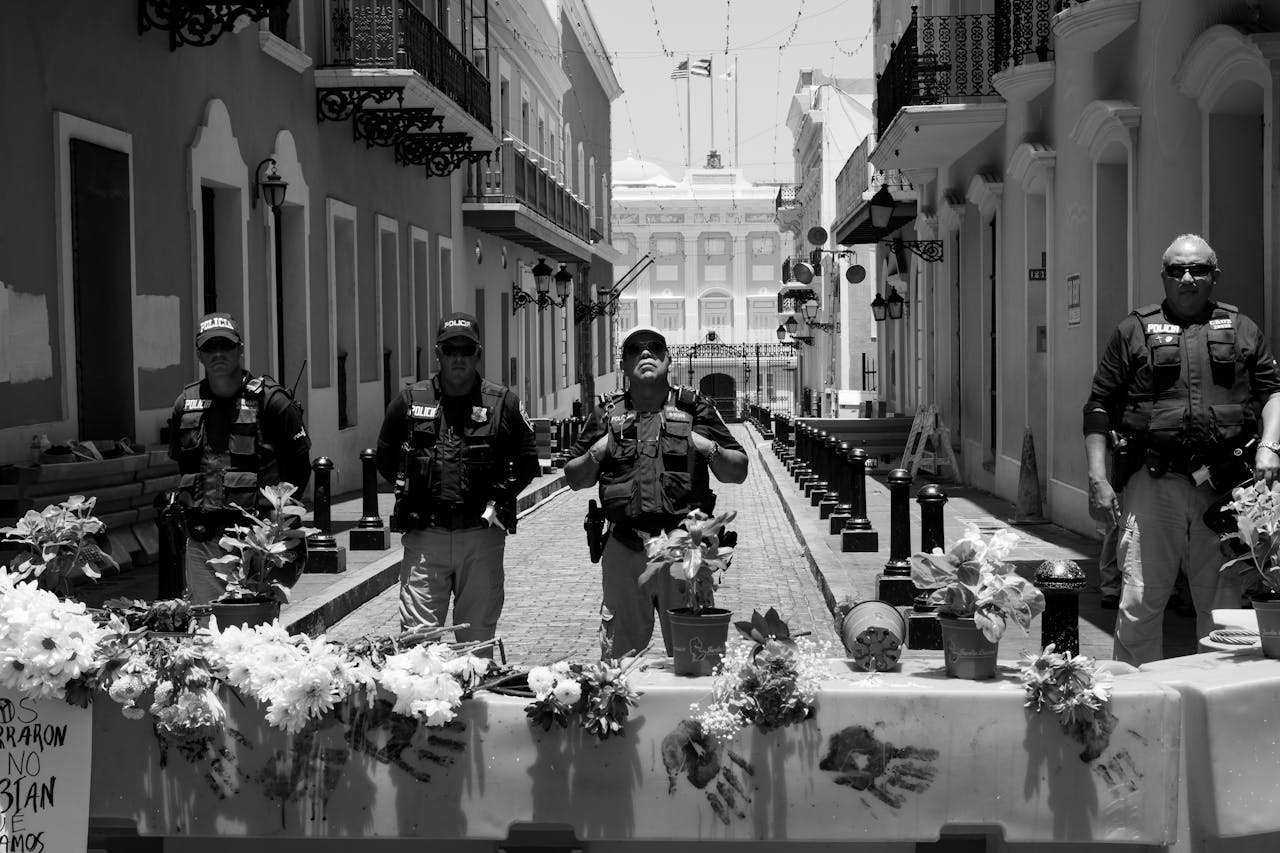 gallery-05 Police officers stand guard behind a flower-adorned barricade on a city street.
